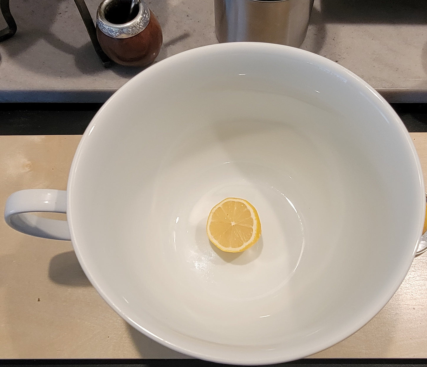 A lemon sits inside of a giant porcelain mug as a size reference. The mug holds 1.5 gallons.